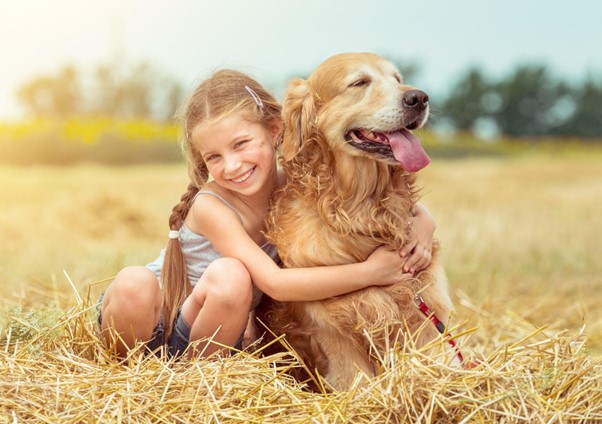 Uma menina abraçada com um Labrador Retriever