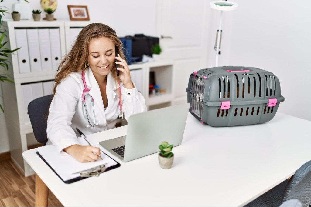 Uma veterinária preenchendo um prontuário, enquanto fala ao telefone.