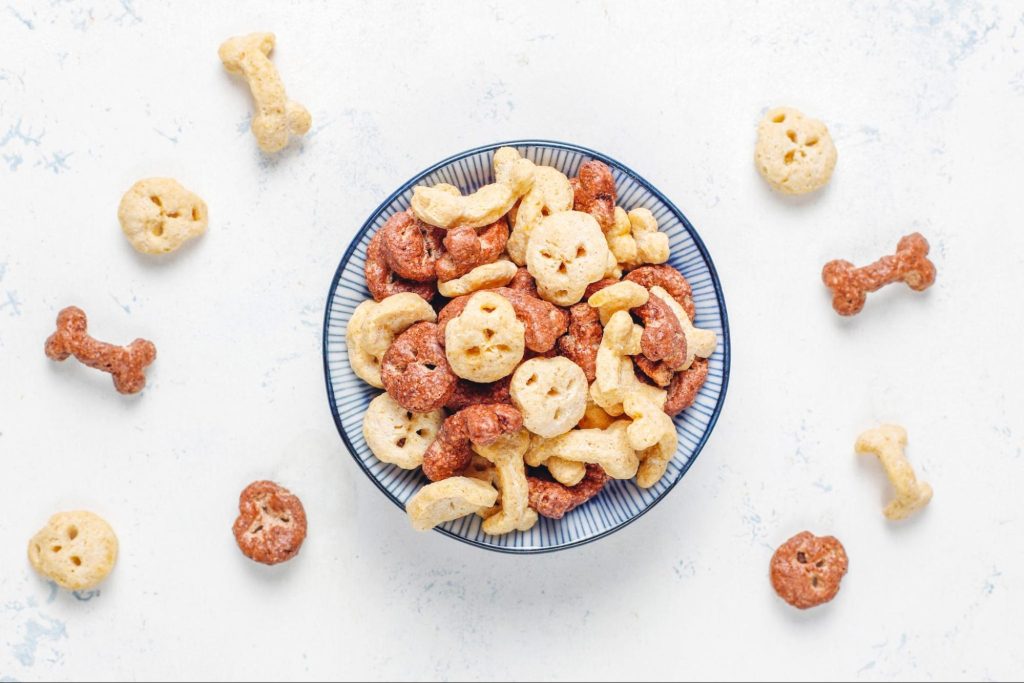 Um recipiente com vários snacks naturais de cães em formatos de ossos e redondos.